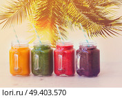 Smoothy drinks in glass jars on white table under plam tree, retro toned. Fresh smoothy drink. Стоковое фото, агентство Ingram Publishing / Фотобанк Лори