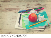 Apple with school supplies on aged white wooden table, retro toned. Apple with school supplies. Стоковое фото, агентство Ingram Publishing / Фотобанк Лори