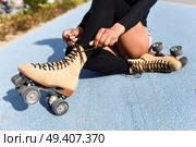 Close-up of black girl sitting on bike line and puts on skates. Unrecognizable woman. Rollerblading concept. Стоковое фото, агентство Ingram Publishing / Фотобанк Лори