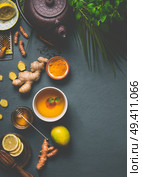 Healthy turmeric spice tea preparation on gray background with teapot, cup of tea,  lemon,  ginger, cinnamon sticks and honey , top view.  Immune boosting remedy , detox and dieting concept. Стоковое фото, агентство Ingram Publishing / Фотобанк Лори