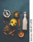 Cup of healthy golden turmeric milk with ingredients: cardamom, fresh turmeric roots, cinnamon, honey and ginger on gray background , top view. Immune boosting remedy , detox and dieting concept. Стоковое фото, агентство Ingram Publishing / Фотобанк Лори