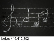 White  music notes with treble clef  on black backgound. Music notes on black. Стоковое фото, агентство Ingram Publishing / Фотобанк Лори