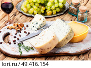 Cheese board served with grapes and nuts on a wooden background. Delicious cheese on the table. Стоковое фото, агентство Ingram Publishing / Фотобанк Лори
