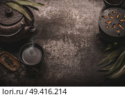 Dark asian tea background with black iron teapot and mug of green tea. Copy space for your design. Authentic vintage style. Traditional tea ceremony arrangement. Стоковое фото, агентство Ingram Publishing / Фотобанк Лори