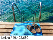A pair of mens leather sandals by steps leading to sea. Стоковое фото, агентство Ingram Publishing / Фотобанк Лори