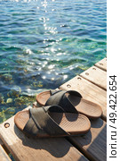 A pair of mens leather sandals on water’s edge by sea. Стоковое фото, агентство Ingram Publishing / Фотобанк Лори