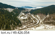 Road serpentine in winter snowy mountain landscape. Aerial rural view of road passing to horizon. Carpathian mountains, Beskids range. Стоковое фото, агентство Ingram Publishing / Фотобанк Лори