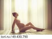 Pregnant young woman over a window background. Стоковое фото, агентство Ingram Publishing / Фотобанк Лори