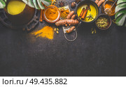 Healthy ingredients border for making turmeric milk drink with fresh turmeric roots , spices and honey on dark background. Hot winter beverage. Immune boosting remedy , detox and dieting concept . Стоковое фото, агентство Ingram Publishing / Фотобанк Лори