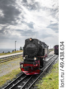 Black locomotive with red color driving on a railtrack under a cloudy sky. Стоковое фото, агентство Ingram Publishing / Фотобанк Лори