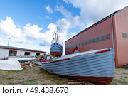 Wooden boat on land with a large ship in the background at the docks. Стоковое фото, агентство Ingram Publishing / Фотобанк Лори