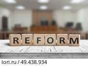 Reform sign on a desk with a blurry background of a court room. Стоковое фото, агентство Ingram Publishing / Фотобанк Лори