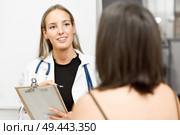 Female doctor explaining diagnosis to her patient. Brunette woman having consultation with smiling blonde girl in medical office.. Female doctor explaining diagnosis to her young woman patient. Стоковое фото, агентство Ingram Publishing / Фотобанк Лори