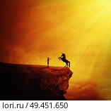 Idyllic view with a boy standing at the edge of a cliff chasm trying to tame a wild unicorn. Begining of a new friendship, fearless symbol. Стоковое фото, агентство Ingram Publishing / Фотобанк Лори
