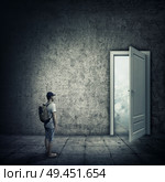 Abstract idea with a person standing in a dark room, in front of a opened door. Escape opportunity, entrance to another world. Стоковое фото, агентство Ingram Publishing / Фотобанк Лори