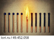 Burning match standing middle a row of whole, new matches at left and extinguished at right. Leadership concept. Стоковое фото, агентство Ingram Publishing / Фотобанк Лори