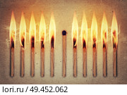 Whole, unused match standing middle a row of burning matches. Standing out from the crowd, leadership concept. Стоковое фото, агентство Ingram Publishing / Фотобанк Лори