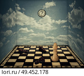 Business idea as a magical room with a chess board floor surrounded by the walls with clouds texture as limitations and the king piece winning in front of beaten pawns laying down. Victory concept. Стоковое фото, агентство Ingram Publishing / Фотобанк Лори