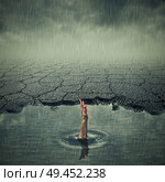 Surrealistic image with a single hand of drowning man asking for help in a pothole of cracked asphalt. Broken pavement with a dirty water puddle in a imaginary town. Стоковое фото, агентство Ingram Publishing / Фотобанк Лори