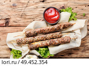 Grilled Lula kebab lamb with sauce on wooden board.Caucasian dish.Shish kebab on stick. Lula kebab on wooden skewers. Стоковое фото, агентство Ingram Publishing / Фотобанк Лори