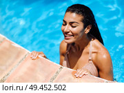 Beautiful Arab woman relaxing in swimming pool with eyes closed. Girl with healthy tanned skin and wet hair enjoying Summer Sun.. Beautiful Arab woman relaxing in swimming pool. . Стоковое фото, агентство Ingram Publishing / Фотобанк Лори