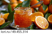 A jar of orange jam is sitting on a plate with a spoon next to it. Стоковое AI-изображение, AI-художник Ярославский Максим / Фотобанк Лори