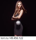 Beautiful young woman in Little black dress. Girl posing on a black background. Blonde girl with long healthy and shiny hair. Care and Beauty. Fashion photo. Glamour lady with a handbag of shiny gems. Стоковое фото, агентство Ingram Publishing / Фотобанк Лори