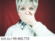 Young androgynous woman with her hand covering her mouth                               . Стоковое фото, агентство Ingram Publishing / Фотобанк Лори