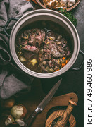 Close up of stewed beef meat in cooking pot with herbs, spices and kitchen utensils, top view. Country’s meat dishes. Slow cooking. Rustic food. Стоковое фото, агентство Ingram Publishing / Фотобанк Лори