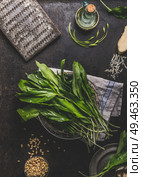 Ramson, wild garlic, leaves bunch on dark rustic kitchen table background with ingredients, top view. Healthy cooking still life. Spring seasonal food. Стоковое фото, агентство Ingram Publishing / Фотобанк Лори