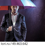 Portrait of a serious, calm businessman holding a colorful umbrella. Стоковое фото, агентство Ingram Publishing / Фотобанк Лори