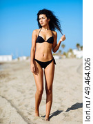 Young arabic woman with beautiful body in swimwear on a tropical beach. Brunette female with curly long hairstyle wearing black bikini.. Young arabic woman with beautiful body in swimwear on a tropical beach. Стоковое фото, агентство Ingram Publishing / Фотобанк Лори