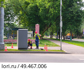 Двое рабочих у электрического шкафа на городской улице. Ремонт неисправного светофора. Редакционное фото, фотограф Мария Сергеева / Фотобанк Лори