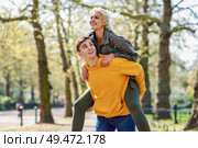 Funny couple in a urban park. Boyfriend carrying his girlfriend on piggyback. Love and tenderness, dating, romance. Lifestyle concept. Funny couple in a urban park. Boyfriend carrying his girlfriend on piggyback. Стоковое фото, агентство Ingram Publishing / Фотобанк Лори