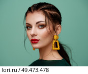 Brunette girl with perfect makeup. Beautiful model woman with curly hairstyle. Care and beauty hair products. Lady with braided hair. Model with jewelry. Turquoise background. Стоковое фото, агентство Ingram Publishing / Фотобанк Лори