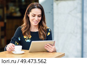 Middle-aged woman using tablet on coffee break in urban cafe bar. Young female sitting at table at cafe. Girl with california highlights hairstyle.. Middle-aged woman using tablet on coffee break in urban cafe bar. Стоковое фото, агентство Ingram Publishing / Фотобанк Лори