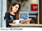 Middle-aged woman using tablet on coffee break in an urban cafe bar. Young female sitting at table at cafe. Girl with california highlights hairstyle.. Middle-aged woman using tablet on coffee break in urban cafe bar. Стоковое фото, агентство Ingram Publishing / Фотобанк Лори