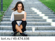 Young businesswoman having a videoconference with her laptop computer sitting on urban steps outdoors.. Middle-age businesswoman working with her laptop computer sitting on the floor. Стоковое фото, агентство Ingram Publishing / Фотобанк Лори
