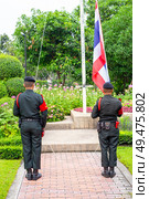 Men in military uniform raising the flag of the Kingdom of Thailand in the public green park Chatuchak, Bangkok, Thailand (2024 год). Редакционное фото, фотограф Коханова Наталья / Фотобанк Лори