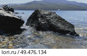 A stone block on the ocean shore is washed by waves and splashes of surf. Стоковое видео, видеограф Кирилл Зотов / Фотобанк Лори