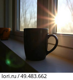 Black mug on the windowsill near the window against the background of the sunrise. Стоковое AI-изображение, AI-художник Анастасия / Фотобанк Лори