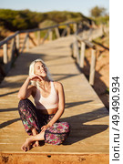 Woman enjoying the sunset on a beautiful beach in Cadiz, Andalusia, Spain. Young female smiling sitting on wooden bridge.. Smiling woman enjoying the sunset on a beautiful beach. Стоковое фото, агентство Ingram Publishing / Фотобанк Лори