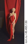Model posing elegantly with red fabric in a dramatic indoor setup. Стоковое видео, видеограф Гурьянов Андрей / Фотобанк Лори