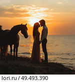 A couple is standing on a beach with a horse in the background. Стоковое AI-изображение, AI-художник Ярославский Максим / Фотобанк Лори