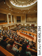 A large room filled with numerous individuals engaging in conversations and activities. Стоковое AI-изображение, AI-художник Данила Большаков / Фотобанк Лори