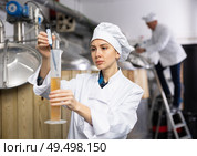 Woman brewmaster measuring beer with alcoholometer. Стоковое фото, фотограф Яков Филимонов / Фотобанк Лори