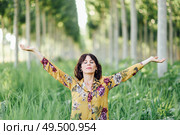 Enjoying the nature. Young woman arms raised enjoying the fresh air in green forest. Female with eyes closed.. Woman arms raised enjoying the fresh air in green forest. Стоковое фото, агентство Ingram Publishing / Фотобанк Лори
