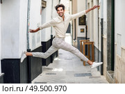 Happy man jumping in the street. Attractive Guy wearing casual clothes in urban background. Male taking a great leap.. Young happy man jumping in the street. Стоковое фото, агентство Ingram Publishing / Фотобанк Лори