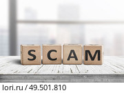 The word scam made of wooden blocks on a table in a bright office room. Стоковое фото, агентство Ingram Publishing / Фотобанк Лори