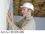 male builder removing old wallpaper. Стоковое фото, агентство Ingram Publishing / Фотобанк Лори